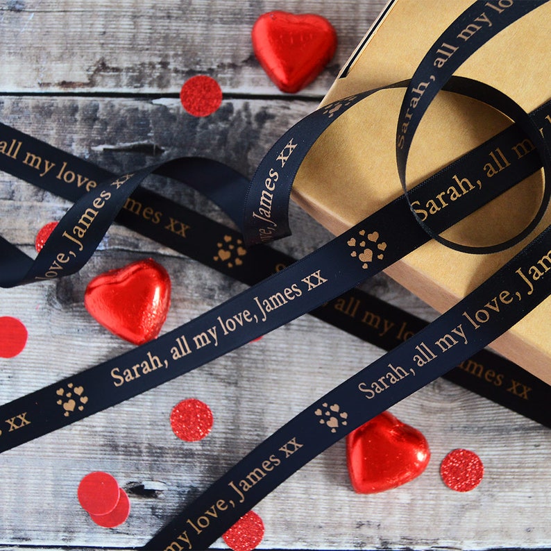 May include: Black satin ribbon with gold lettering and paw prints. The ribbon reads "Sarah, all my love, James xx".