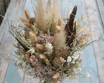 May include: A dried flower bouquet with a rustic, natural aesthetic. It features a variety of dried grasses, flowers, and feathers in shades of beige, brown, and pink.
