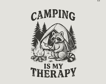 May include: A black and white illustration featuring a raccoon roasting a marshmallow over a campfire in front of a tent. The text reads "CAMPING IS MY THERAPY". The design includes pine trees and a light beige background.