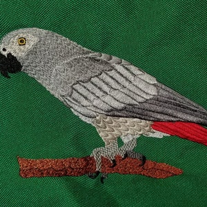 Könnte beinhalten: Grauer Papagei mit roten Schwanzfedern, gestickt und auf einem braunen Ast vor grünem Hintergrund sitzend.