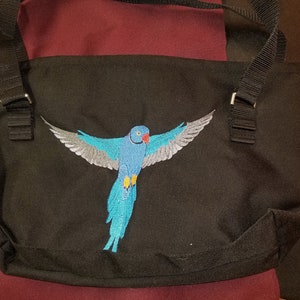 May include: Black canvas tote bag with an embroidered blue and gray parrot design.