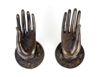 Pair of hands of Buddha abhaya-mudrā in brass, with an aged dark patina.
