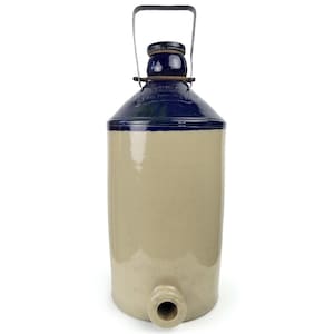 May include: A vintage stoneware water cooler with a blue and tan color scheme. The cooler has a cylindrical body, a blue lid, and a metal handle. It features a spigot near the base for dispensing liquids. A classic piece for rustic decor.