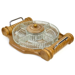 Peut inclure: Un plateau de service en bois avec un bol en verre divisé en sections. Le bol a un couvercle avec un petit bouton doré. Le plateau a deux poignées en bois.