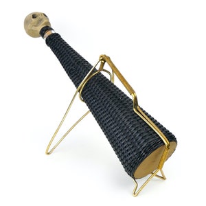May include: A black wicker bottle holder with a skull-shaped top and a gold metal stand.