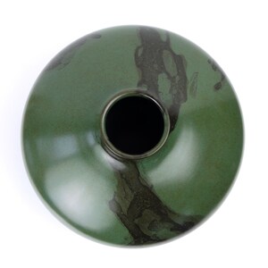 May include: A green ceramic vase with a wide opening and a dark green glaze. The glaze has a mottled effect, creating a unique pattern.