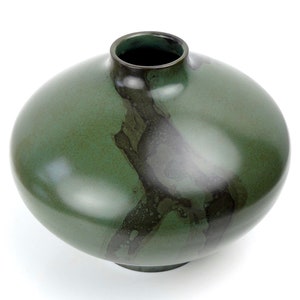 May include: A round, green ceramic vase with a dark green glaze and a mottled, abstract design.