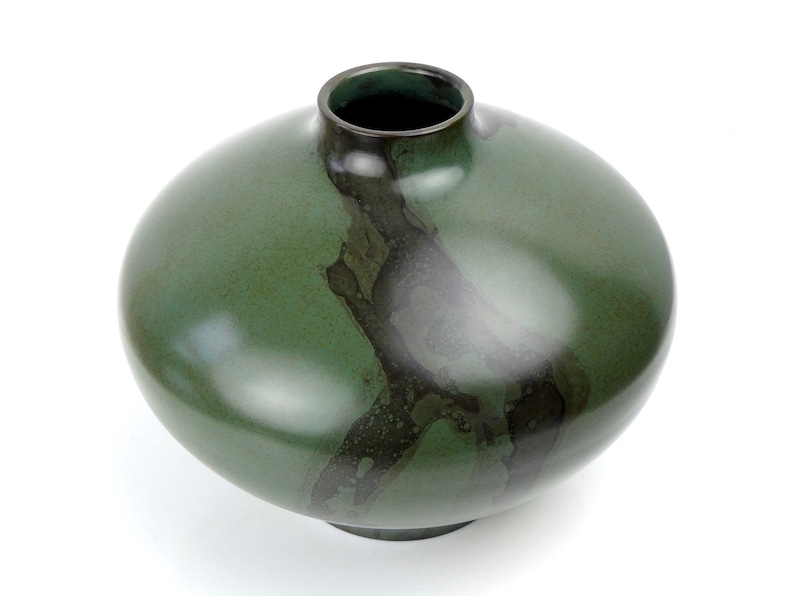 May include: A round, green ceramic vase with a dark green glaze and a mottled, abstract design.