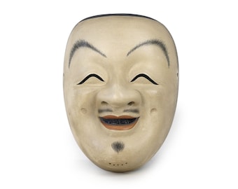 May include: A traditional Japanese Noh mask with a smiling expression. The mask is made of wood and painted in shades of beige, brown, and black. The mask features a wide mouth, closed eyes, and a prominent nose.