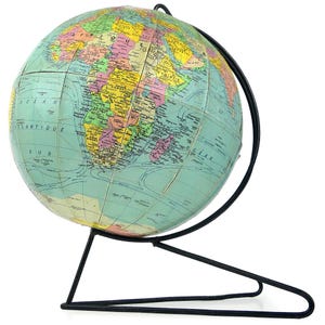 Könnte beinhalten: Ein Globus mit einer farbenfrohen Karte von Afrika und den umliegenden Ozeanen, montiert auf einem dünnen schwarzen Metallständer. Der Globus zeigt verschiedene Länder in Gelb-, Rosa- und Grüntönen mit schwarzen Textbeschriftungen.