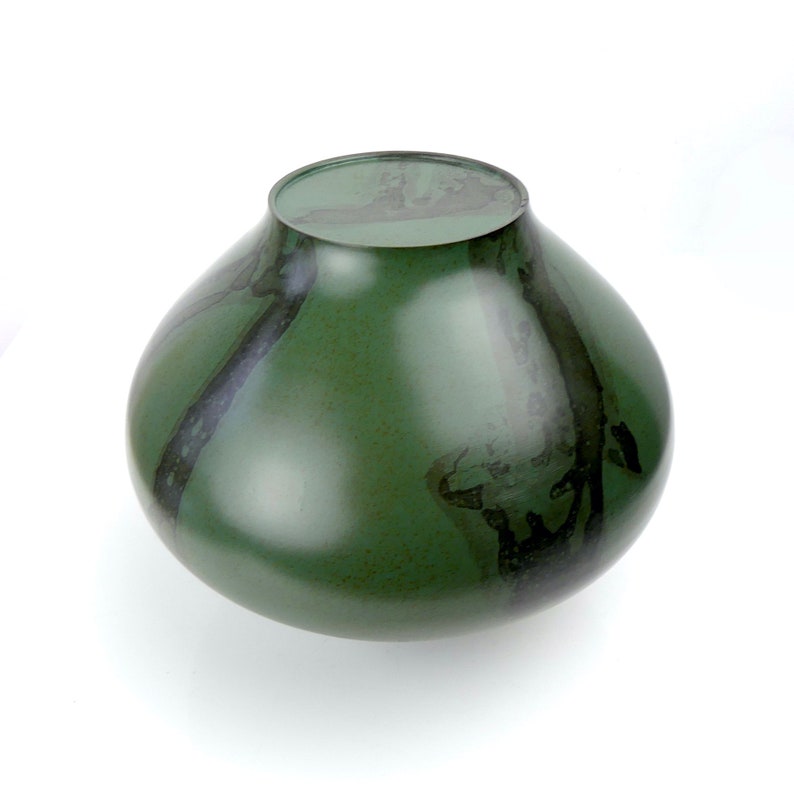 May include: A round, green ceramic vase with black swirling patterns. The vase has a wide base and a narrow neck.