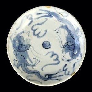Peut inclure: Une assiette en céramique blanche avec un motif bleu et blanc de deux dragons. Les dragons sont représentés dans un motif tourbillonnant avec leurs queues entrelacées. L'assiette a un bord légèrement ébréché.