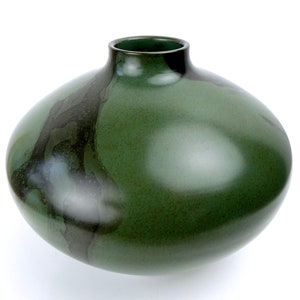 May include: A large, round, green ceramic vase with a dark green and black glaze. The vase has a wide mouth and a rounded bottom.