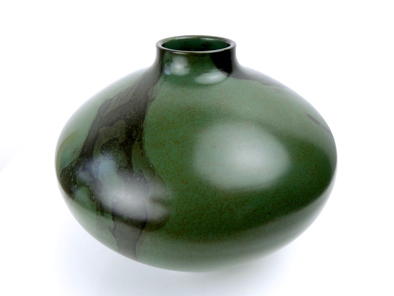 May include: A large, round, green ceramic vase with a dark green and black glaze. The vase has a wide mouth and a rounded bottom.