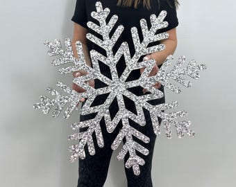 May include: A large silver glitter snowflake decoration. The snowflake is made of cardboard and has a sparkly finish.