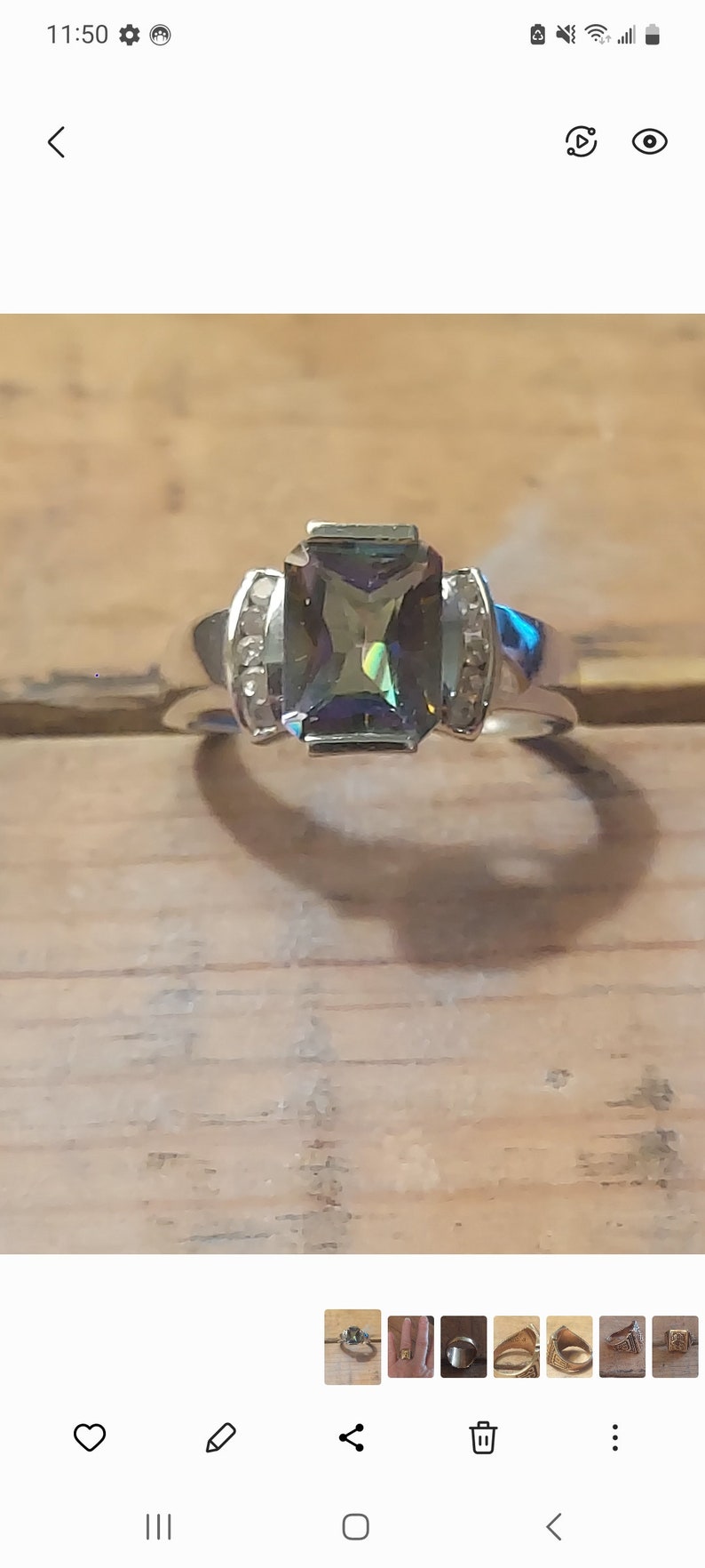 May include: A silver ring with a large, rectangular, iridescent green gemstone surrounded by smaller clear gemstones.