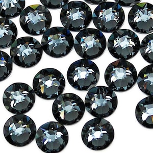 Puede incluir: Una dispersión de piedras de cristal redondas y facetadas de color gris oscuro. Las piedras de cristal tienen un ligero brillo iridiscente.