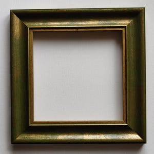 Puede incluir: Un marco de imagen verde con un borde interior dorado. El marco tiene un diseño simple y clásico.