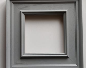 May include: A gray picture frame with a simple, slightly raised, rectangular molding. The frame is made of wood and has a distressed finish.