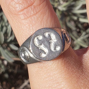 May include: A silver signet ring with a black oval stone featuring the engraved letters "SS".