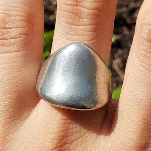 May include: A silver ring with a large, rounded, dome-shaped top.