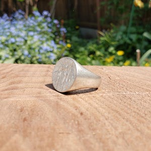 May include: A silver signet ring with a detailed design of an eagle on the face.