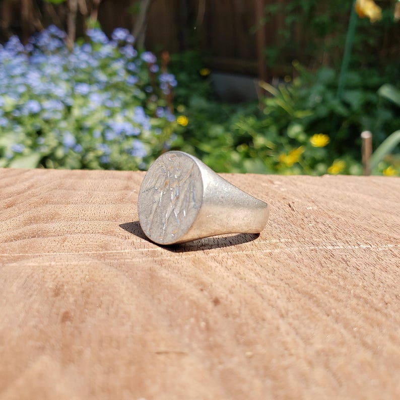 May include: A silver signet ring with a detailed design of an eagle on the face.