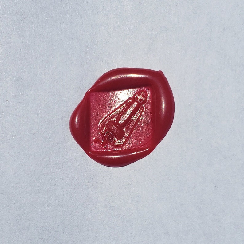 May include: A red wax seal with a raised design of a rocket ship.