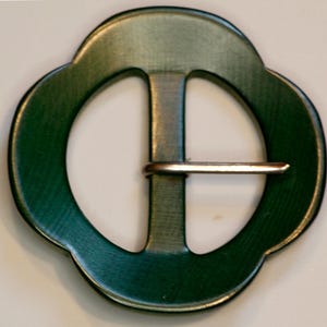 May include: A green metal buckle with a smooth, rounded shape and a silver metal bar.