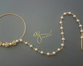 May include: Gold nose ring with a chain of white pearls and a small gold hook at the end. The nose ring has a small cluster of gold beads with clear rhinestones.