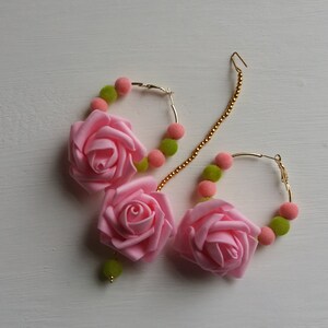 May include: A pair of gold hoop earrings with pink fabric rose accents and green and pink beads.