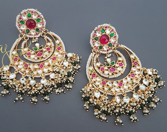 May include: A pair of gold earrings with a crescent moon design. The earrings are adorned with pink, green, and white stones and have a dangling chain of pearls and green beads.