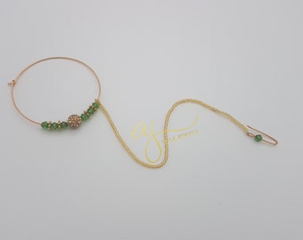 May include: Gold nose ring with a green beaded chain and a small, sparkly, gold ball charm.