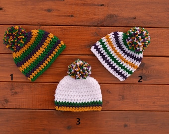 May include: Three crocheted hats with pom-poms in green, purple, gold, and white stripes. The hats are numbered 1, 2, and 3.