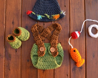 May include: A crocheted baby outfit in green, brown, and blue, with a matching hat. The outfit includes a diaper cover with suspenders, booties, and a fishing pole with a fish.