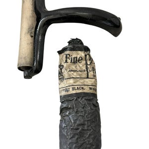 Könnte beinhalten: Ein schwarzer Druckwalze mit Holzrolle und Griff, neben einer Tube schwarzer Tinte. Die Tintenröhre hat ein zerrissenes Etikett mit den Worten "Fine Print Black" sichtbar.