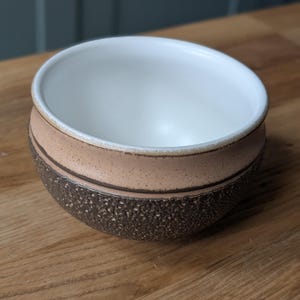 Puede incluir: Un juego de tres tazas de cerámica con un acabado mate moteado. Las tazas son en tonos crema, gris claro y gris oscuro. Cada taza tiene un diseño simple y minimalista, perfecto para café o té.
