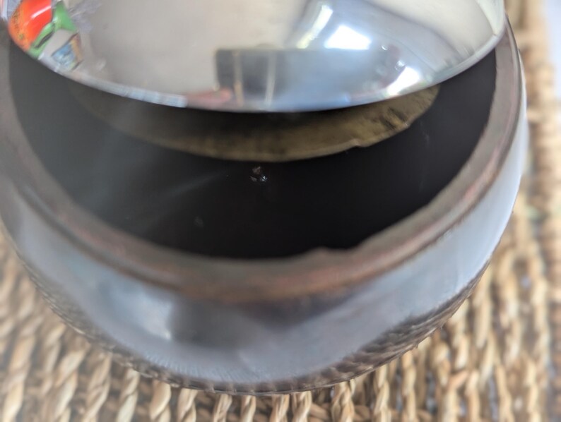 Peut inclure: Un pot en c&eacute;ramique brun fonc&eacute; avec un couvercle argent&eacute;. Le couvercle est l&eacute;g&egrave;rement entrouvert, r&eacute;v&eacute;lant l'int&eacute;rieur du pot.