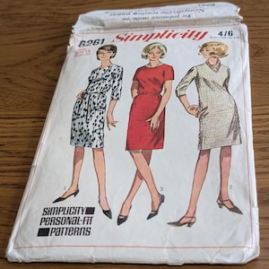 Könnte beinhalten: Ein Vintage-Schnittmusterumschlag von Simplicity 6261 mit Illustrationen von drei verschiedenen Kleidungsstilen. Der weiße Papierumschlag zeigt das Simplicity-Logo, die Schnittnummer 6261 und den Text Simplicity Personal-Fit Patterns.