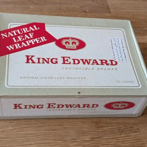 Könnte beinhalten: Eine rechteckige Schachtel mit King Edward Invincible Deluxe Zigarren. Die Schachtel ist hellgrün mit roten und goldenen Akzenten. Der Text "NATURAL LEAF WRAPPER" befindet sich auf einem roten Banner. Die Schachtel trägt auch den Text "KING EDWARD" und "50 CIGARS".
