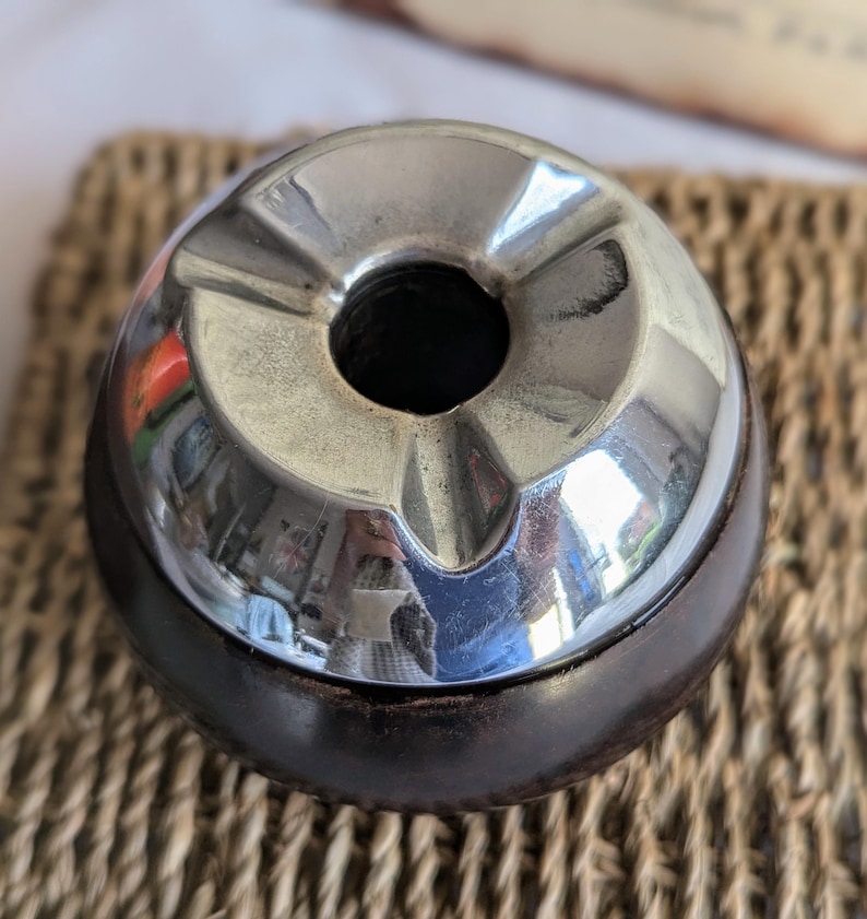 Peut inclure: Un cendrier vintage en chrome et bois avec une forme ronde et un bol profond. Le cendrier a une surface r&eacute;fl&eacute;chissante et une base en bois fonc&eacute;.