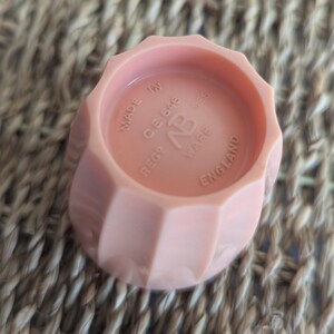 Peut inclure: Un bouchon de bouteille en plastique rose avec le texte "REGD. CE648 NP WARE MADE IN ENGLAND" sur le dessus.