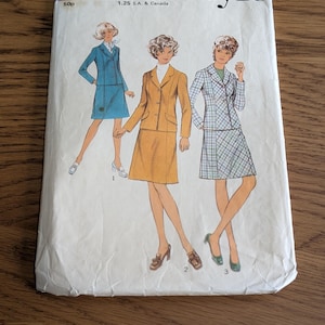 Könnte beinhalten: Ein Vintage-Schnittmusterumschlag von Style mit der Nummer 3966, Größe 14, Oberweite 36. Die Vorderseite zeigt Illustrationen von drei Rockanzügen: einen blauen, einen senfgelben und einen weißen mit blauem Karomuster, jeweils mit Blazer und Rock.