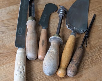 Una colección de utensilios de cocina antiguos con mango de madera.