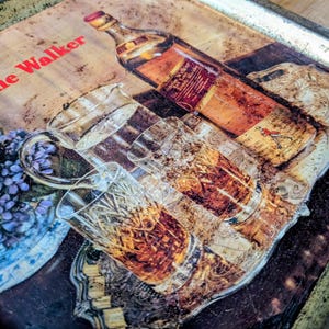 May include: Vintage metal serving tray with a whiskey bottle, glasses, and a floral arrangement. The tray features the text "Johnnie Walker" in red. The image has a warm, aged aesthetic.