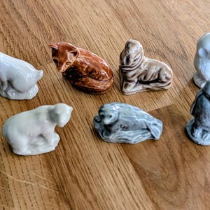 Peut inclure: Ensemble de figurines d'animaux en céramique, comprenant un lapin, un renard, un ours, un phoque, un hibou et un pingouin. Les figurines sont de couleurs variées, comme le blanc, le marron et le gris, sur une surface en bois.