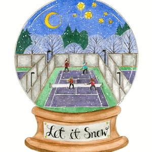 May include: A snow globe with a winter scene of people playing tennis on a court. The globe is on a wooden base with the words "Let it Snow" written on it.
