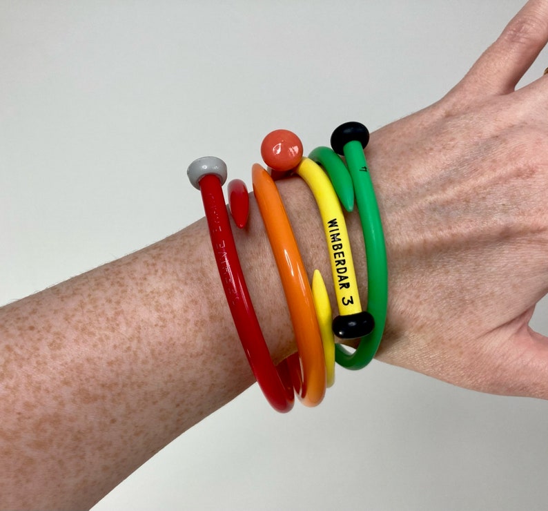 May include: A set of five colorful plastic bracelets with a black and white label that reads "WIMBERDAR 3".