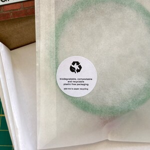 May include: A white paper bag with a green circle on it. The circle has a recycling symbol and the text "biodegradable, compostable and recyclable plastic free packaging add me to paper recycling".