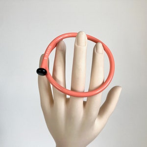 May include: A pink plastic bangle with a black dot and the text "DUREX 5" on the side.